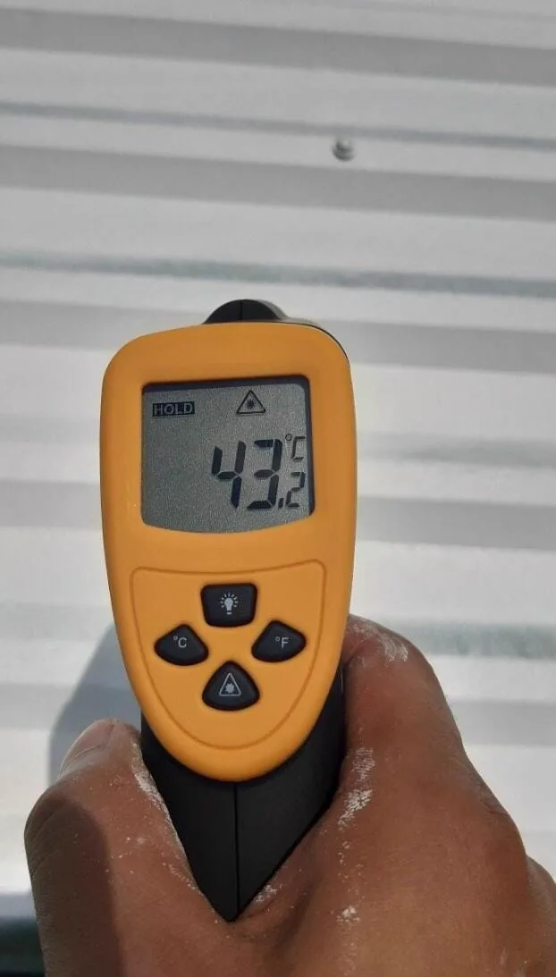 Infrared thermometer reading 43.2&deg;C on a white reflective coated metal roof